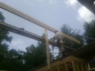 Carpenter setting a ridge beam over a new addition frame — Ice Dam Removal by Roofing Brothers in Karval