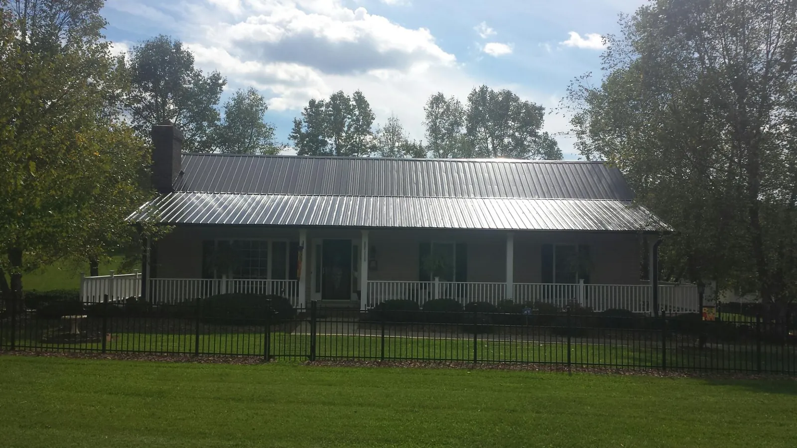 Gray metal roof on a brick ranch with a full width front porch — Gutter Guard Installation work by our crew in Karval