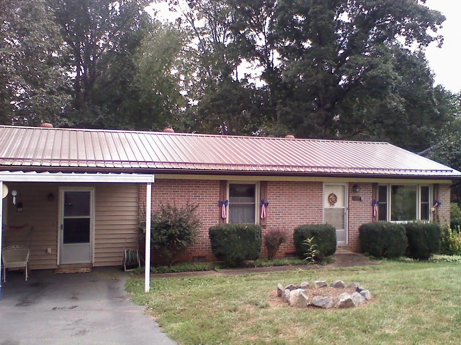 Bronze metal roof and carport on a brick ranch home — Roof Repair work by our crew in Karval